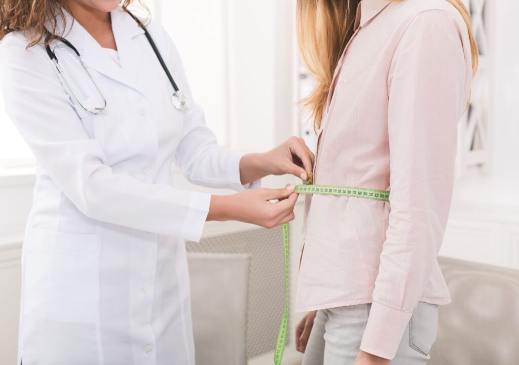 Ärztin misst den Bauchumfang einer Frau – Abnehmspritze Eignung nach BMI und medizinischen Voraussetzungen