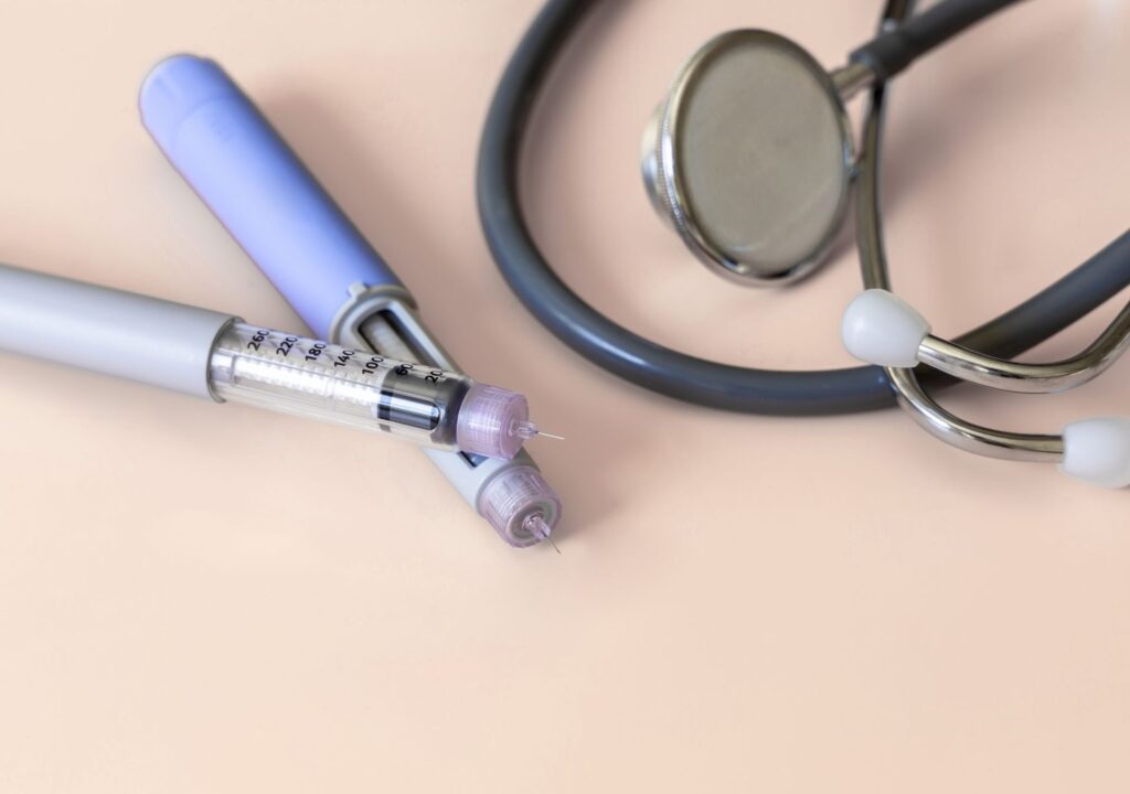 Zwei Abnehmspritzen-Pens neben einem Stethoskop – Symbolbild für medizinische Anwendung und Erfahrungen von DoktorABC Nutzer:innen
