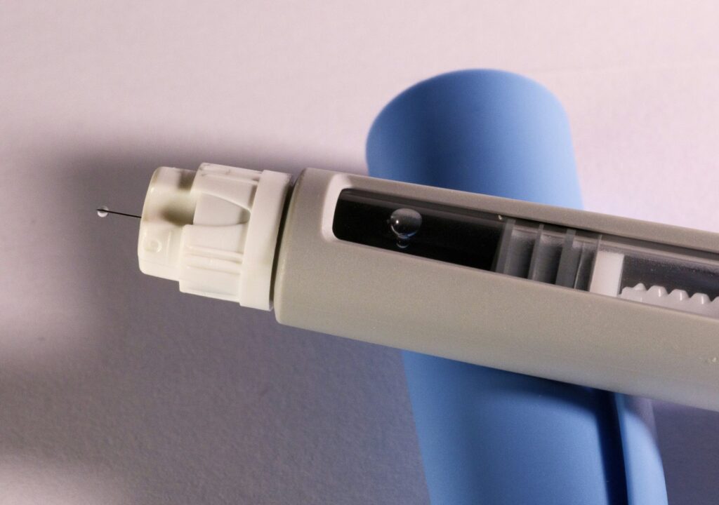 Nahaufnahme eines Abnehmspritzen-Pens mit Nadel und Flüssigkeitstropfen – Beispiel für verschreibungspflichtige Medikamente wie bei DoktorABC