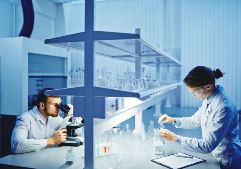 Zwei Wissenschaftler im modernen Labor untersuchen die Wirksamkeit von GLP-1 Abnehmspritzen unter dem Mikroskop und mit Probenanalyse