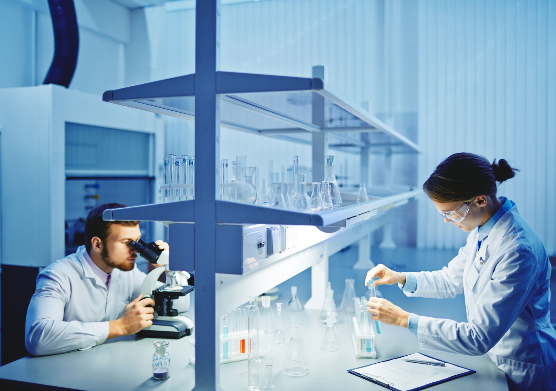 Zwei Wissenschaftler im modernen Labor untersuchen die Wirksamkeit von GLP-1 Abnehmspritzen unter dem Mikroskop und mit Probenanalyse