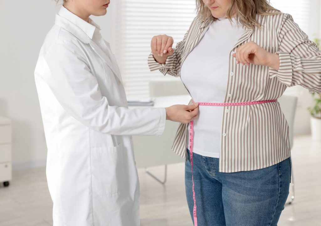 Ärztin misst den Taillenumfang einer Patientin – Symbolbild für die Stabilisierung des Gewichts nach dem Absetzen der Abnehmspritze