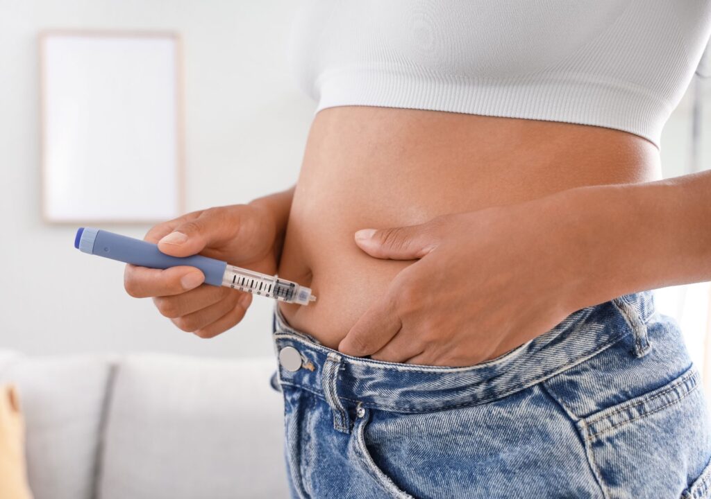 Frau setzt eine Abnehmspritze am Bauch an – symbolisch für den Antrag auf Kostenübernahme mit ärztlicher Begründung und medizinischer Dokumentation